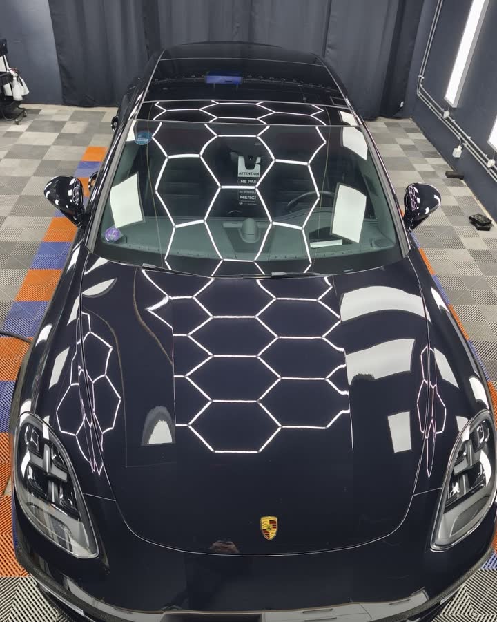 Le capot d’une Porsche noire, reflets de l’éclairage